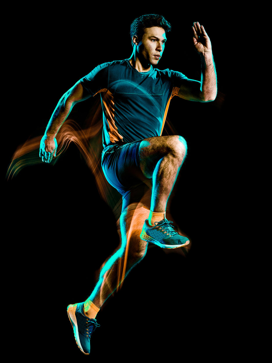 Man in athletic wear leaping in a dark background